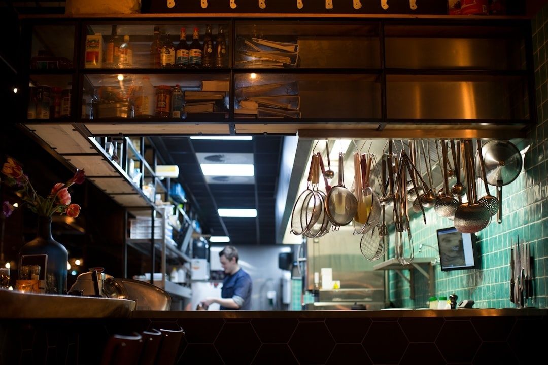 Narrow restaurant galley with hanging utensils and a cook at work