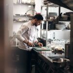 Chef chopping ingredients at a compact galley kitchen workstation
