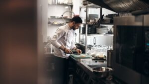 Chef chopping ingredients at a compact galley kitchen workstation
