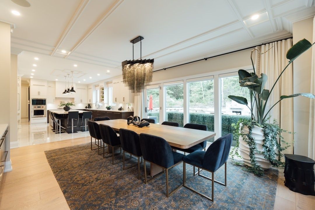Elegant dining room with upholstered chairs, rug, and pendant lighting